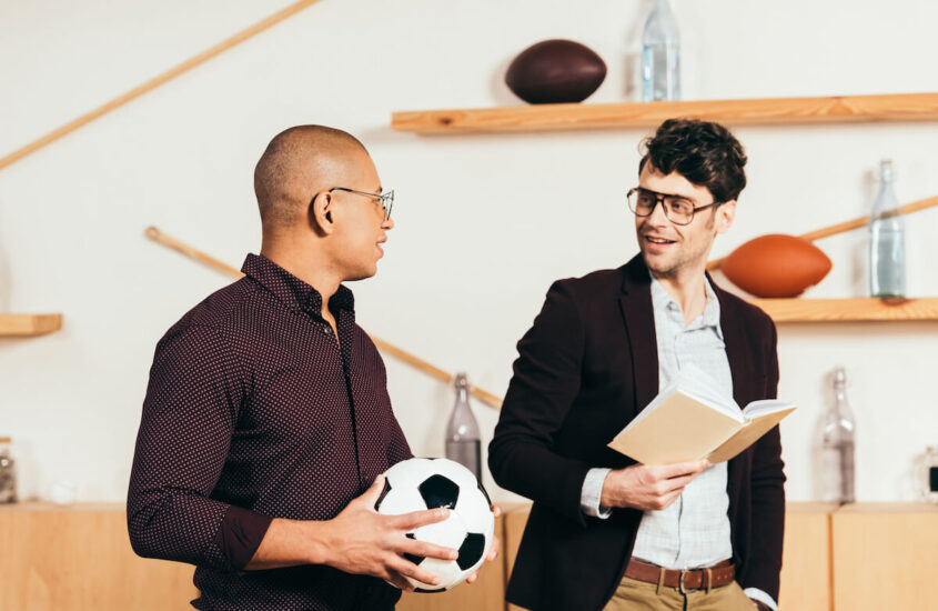 mężczyźni czytają książki o sporcie i niosą piłkę do futbolu